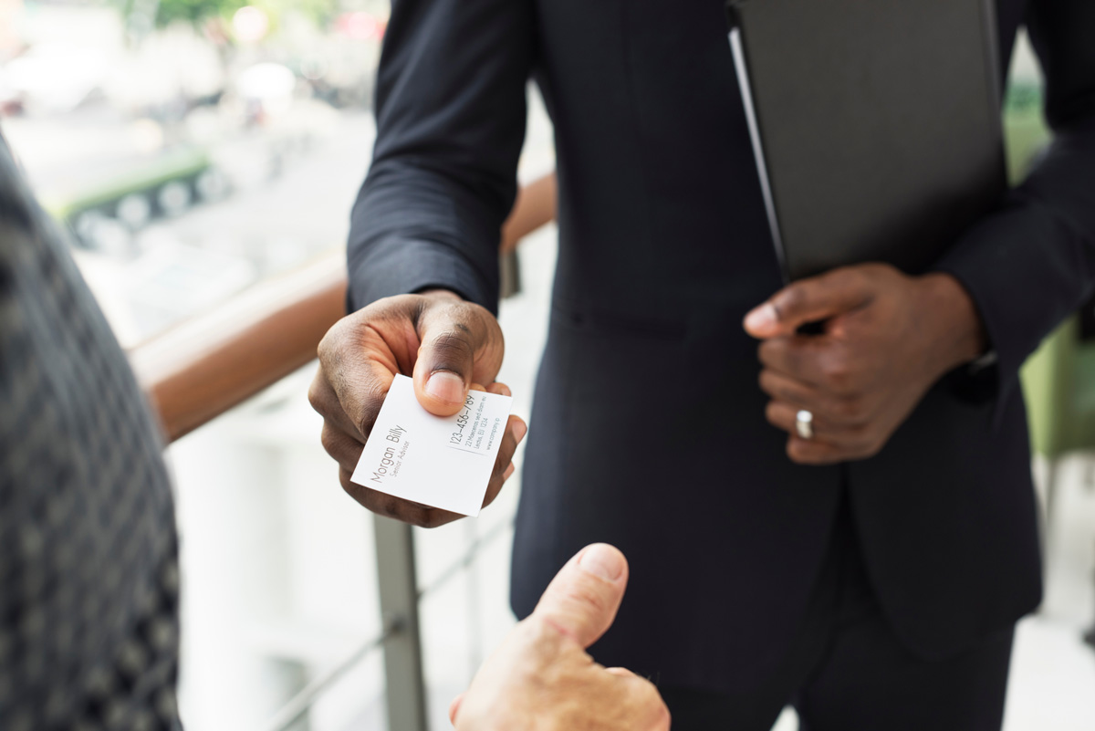 A person handing another person a white business card in El Paso.